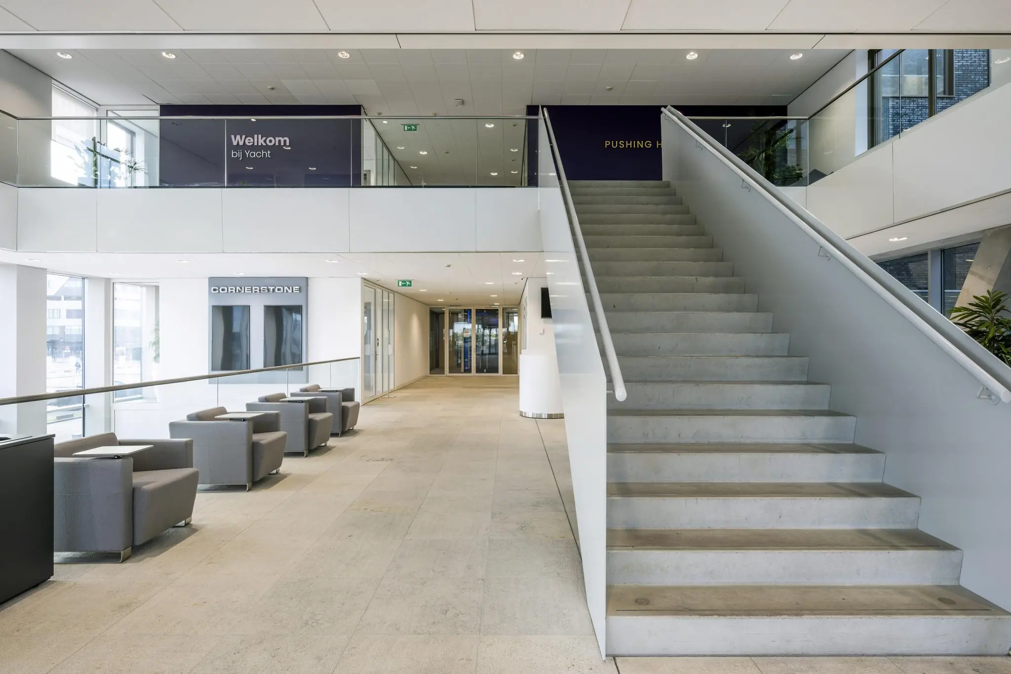 Moderne entreehal van een kantoorgebouw aan het Rotterdam Airportplein met zitgedeelte en trap naar de eerste verdieping.